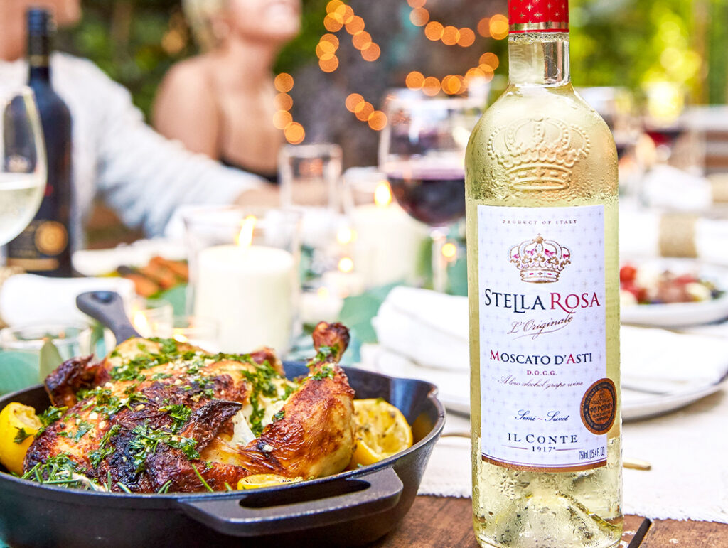 A bottle of Stella Rosa Moscato D'asti on a table with food. Fall wine and food pairing.