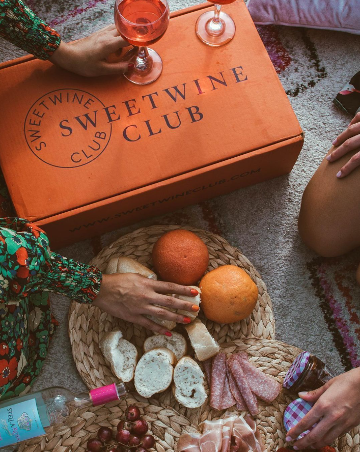 Sweet Wine Club Box on the floor by a charcuterie board.